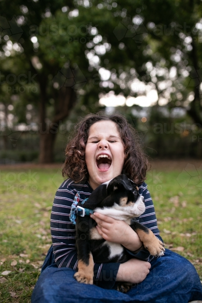 Happy girl outside holding pet bulldog puppy - Australian Stock Image
