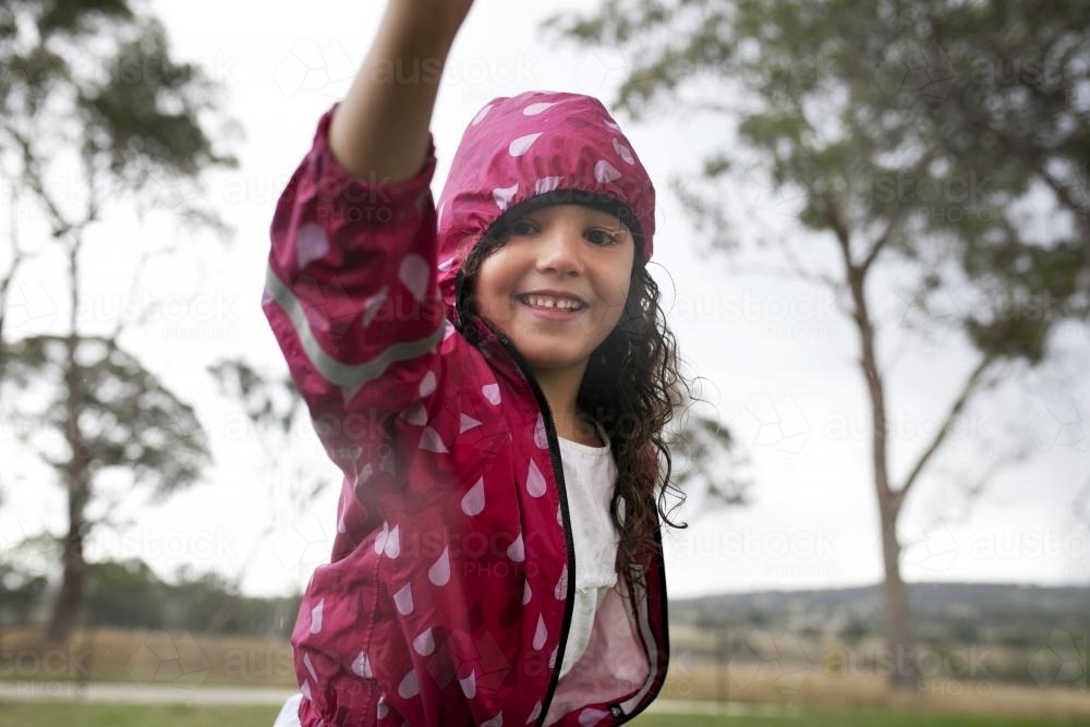 Happy girl wearing pink raincoat outside - Australian Stock Image