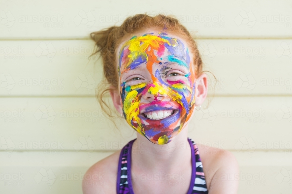 Happy girl with brightly coloured face paint - Australian Stock Image