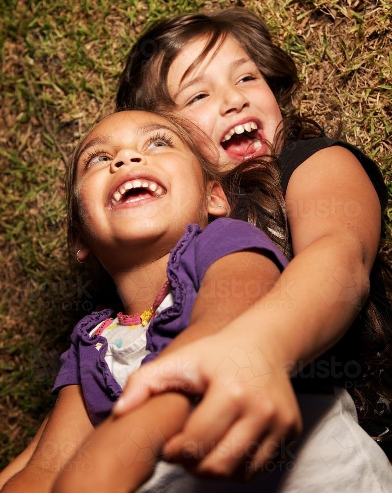 Happy Girls Rolling on the Ground - Australian Stock Image