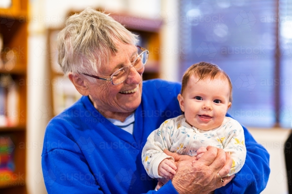 Happy great grandmother holding baby great grandchild - Australian Stock Image