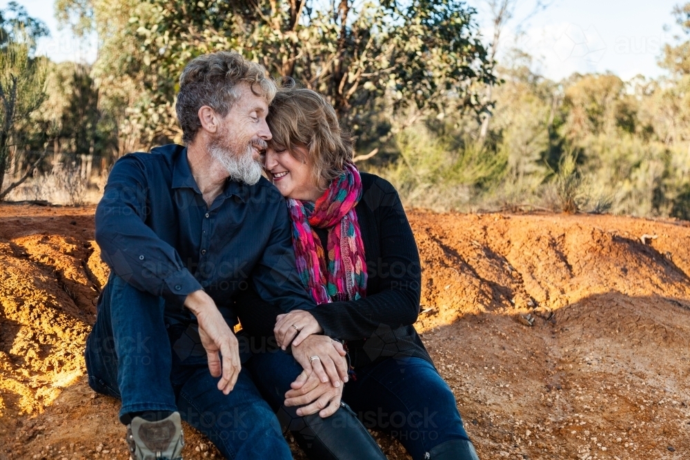 Happy husband and wife sitting together outside - Australian Stock Image