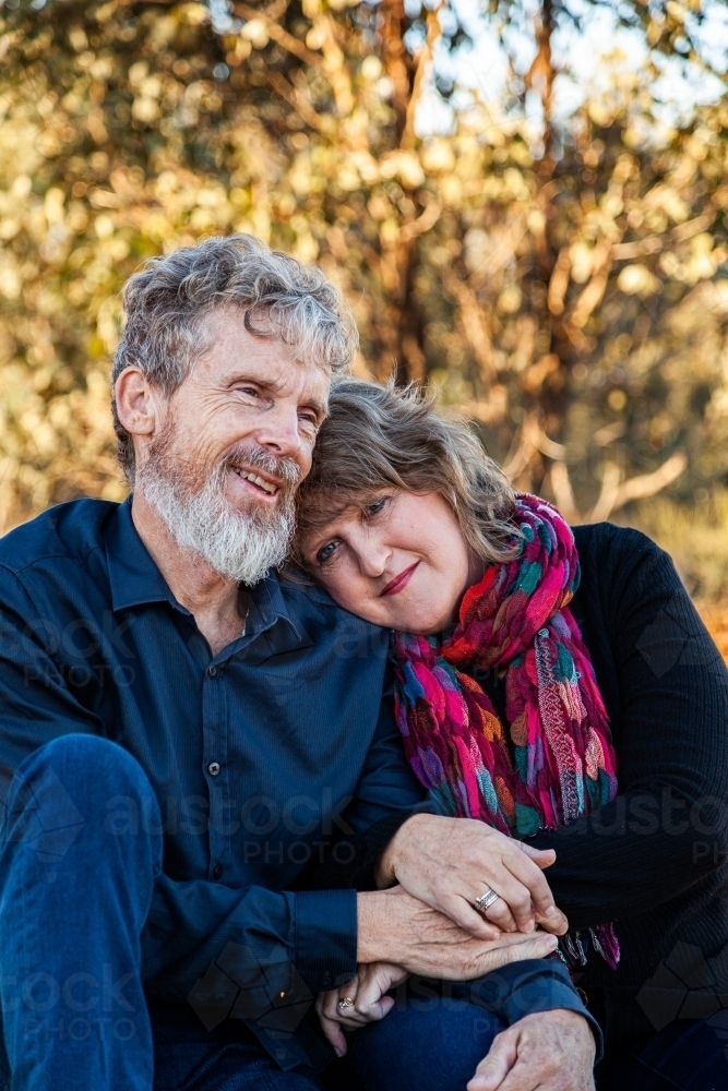Happy husband and wife sitting together outside - Australian Stock Image