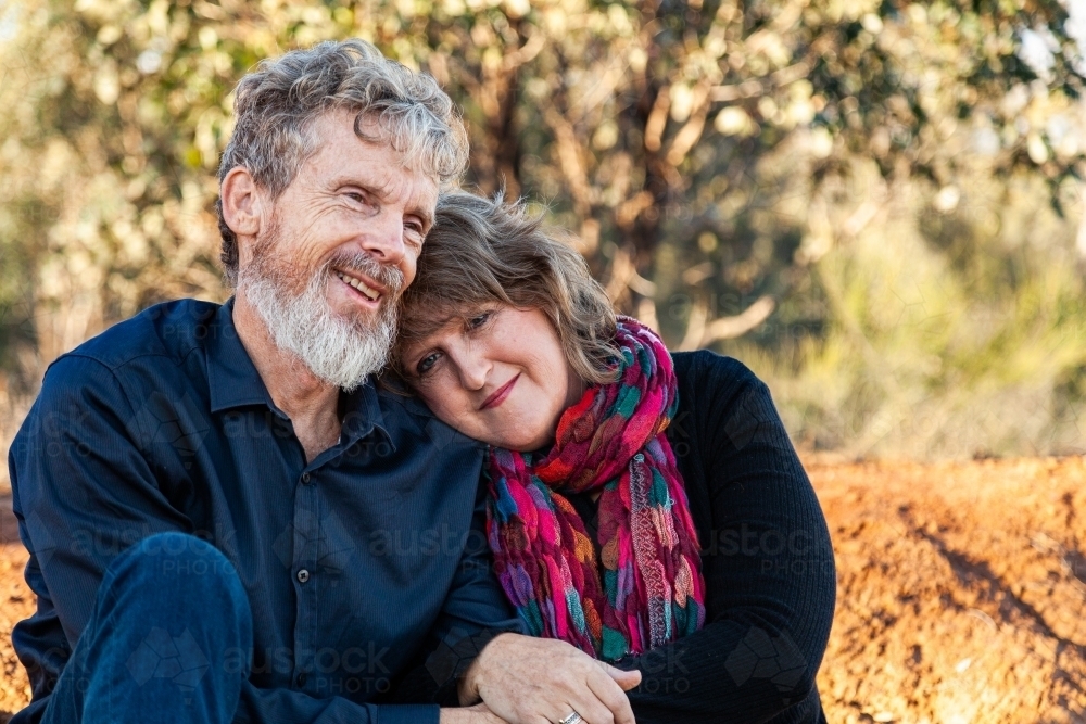 Happy husband and wife sitting together outside - Australian Stock Image