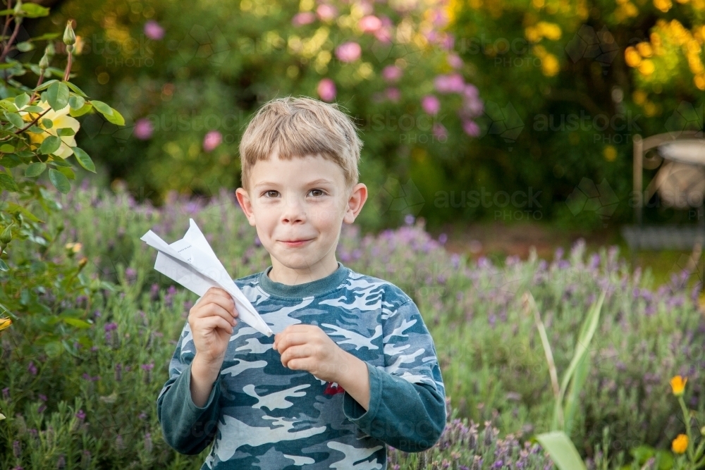Happy kid making and flying paper planes in the garden - Australian Stock Image