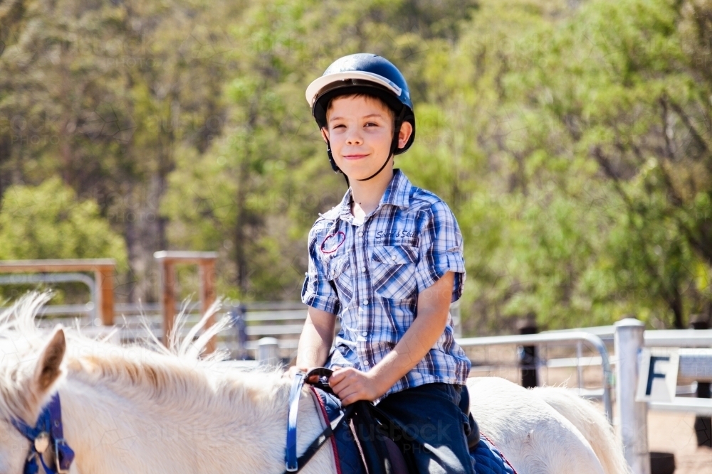 Happy kid on white pony - riding lessons - Australian Stock Image