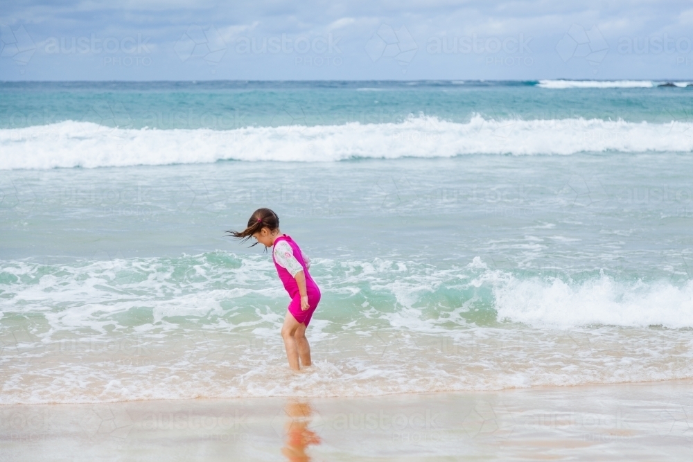 Happy kid running and splashing in seaside waves at the beach - Australian Stock Image