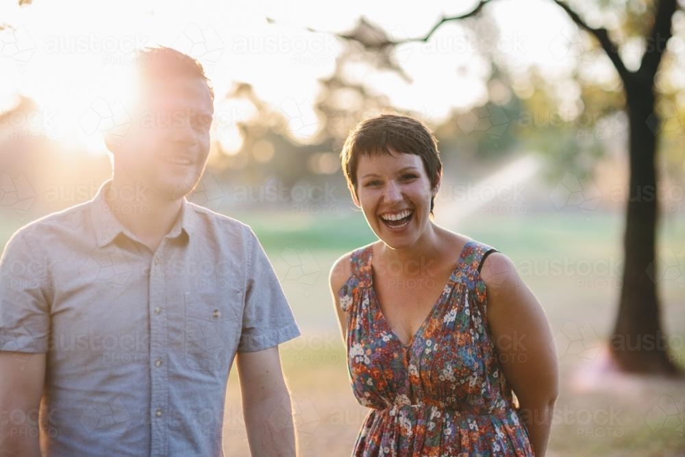 Happy laughing couple in park at sunset - Australian Stock Image