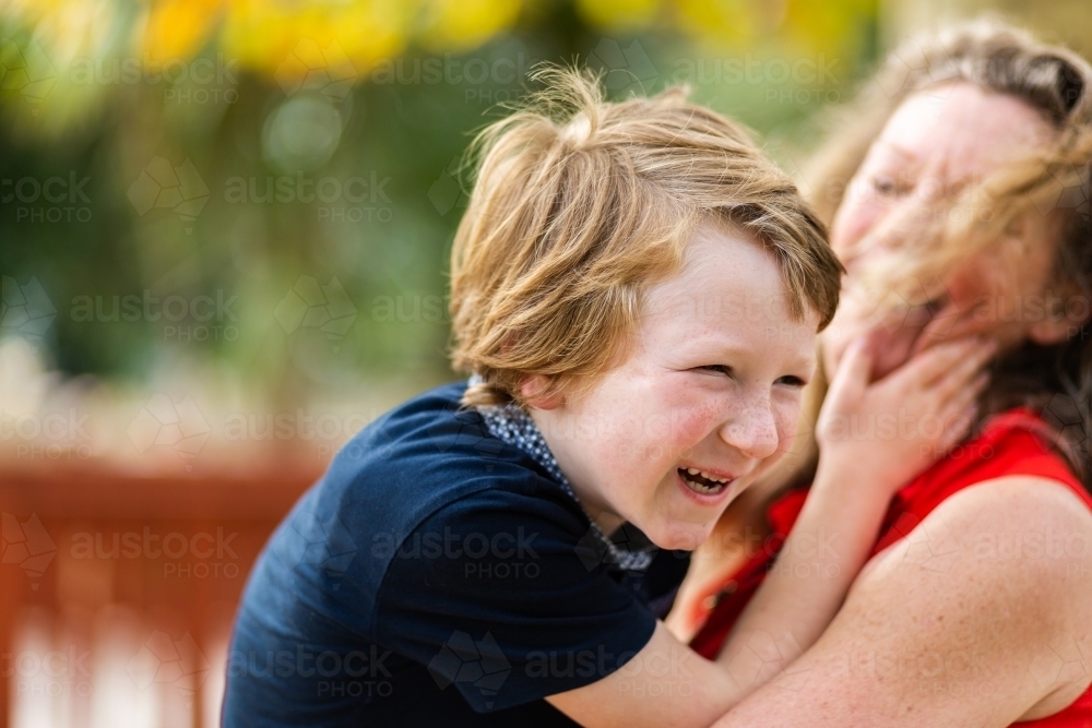 Happy little autistic boy laughing and hugging his grandmother - Australian Stock Image