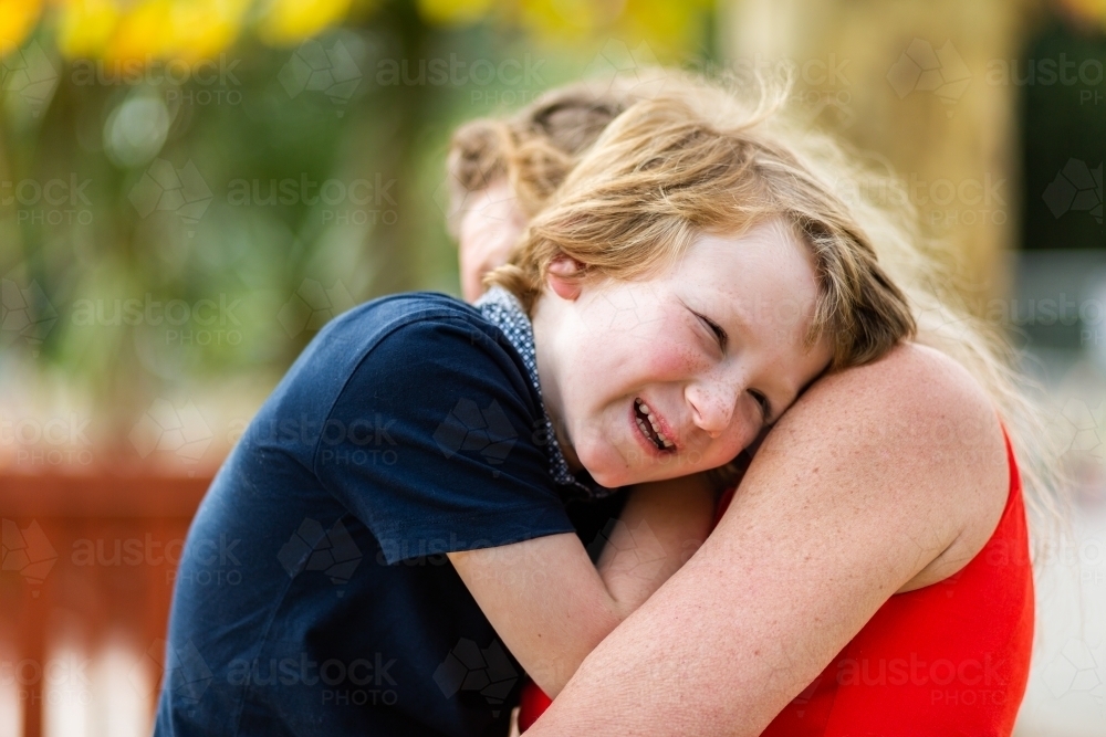 Happy little autistic boy laughing and hugging his grandmother - Australian Stock Image
