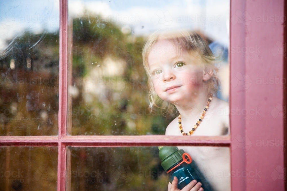 Happy little boy looking out window - Australian Stock Image