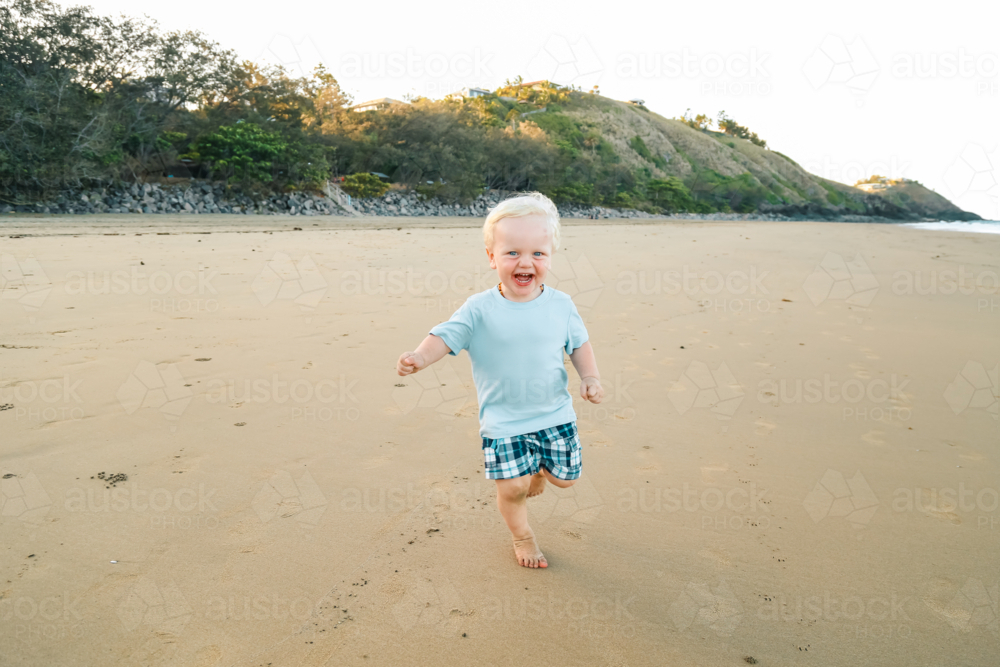 Happy little boy running on the beach - Australian Stock Image