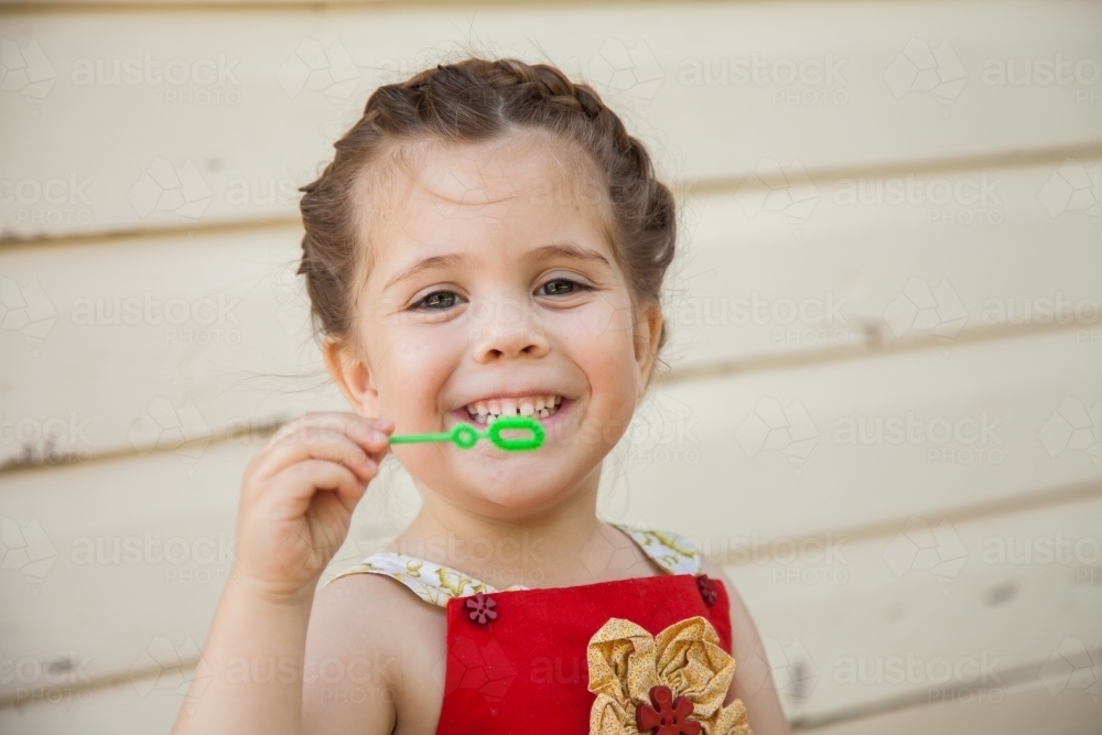 Happy little girl blowing bubbles outside - Australian Stock Image