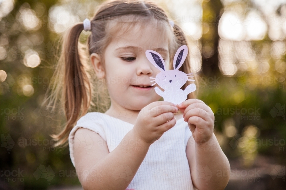 Happy little girl holding a homemade Easter bunny in the garden - Australian Stock Image