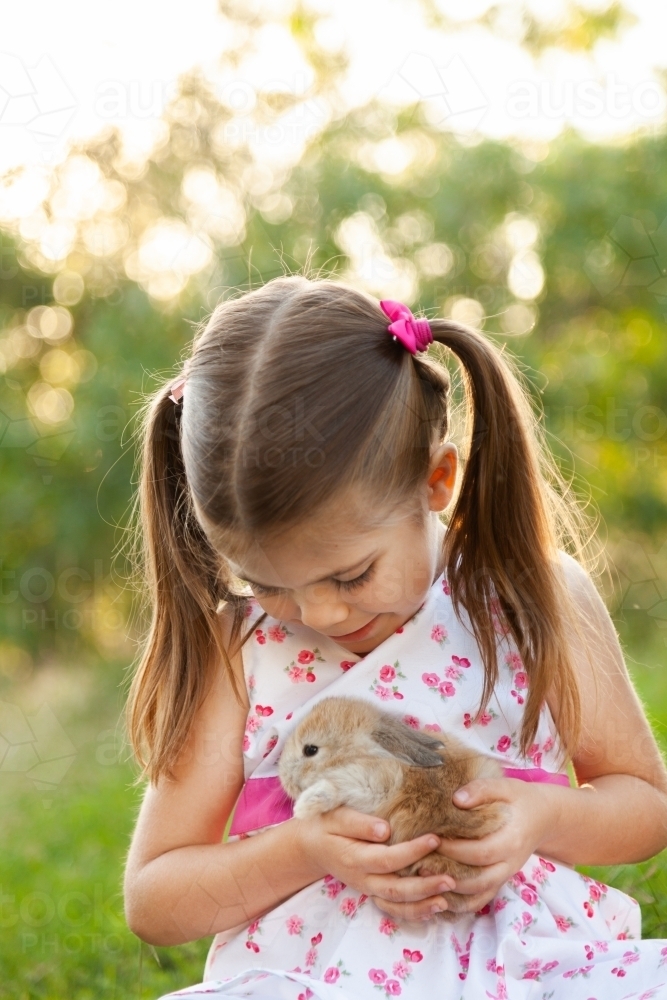 Happy little girl holding an Easter bunny pet rabbit - Australian Stock Image