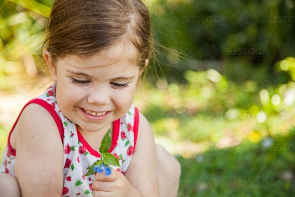 Happy little girl holding flower of wandering jew plant - Australian Stock Image