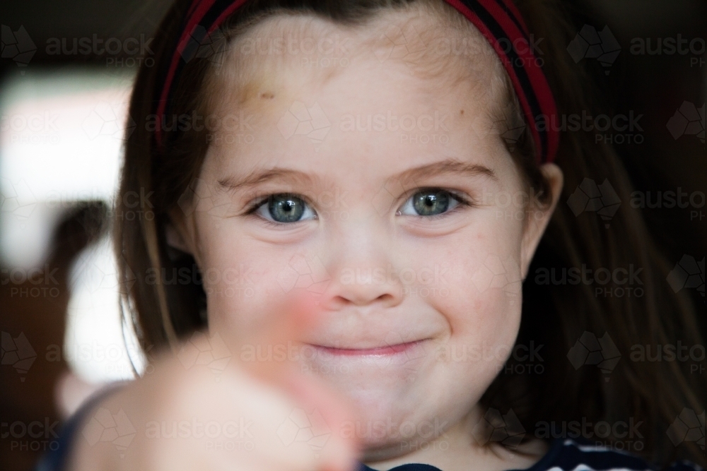 Happy little girl pointing at camera focus on face - Australian Stock Image