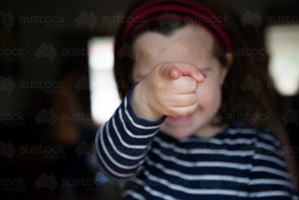 Happy little girl pointing at camera focus on finger - Australian Stock Image