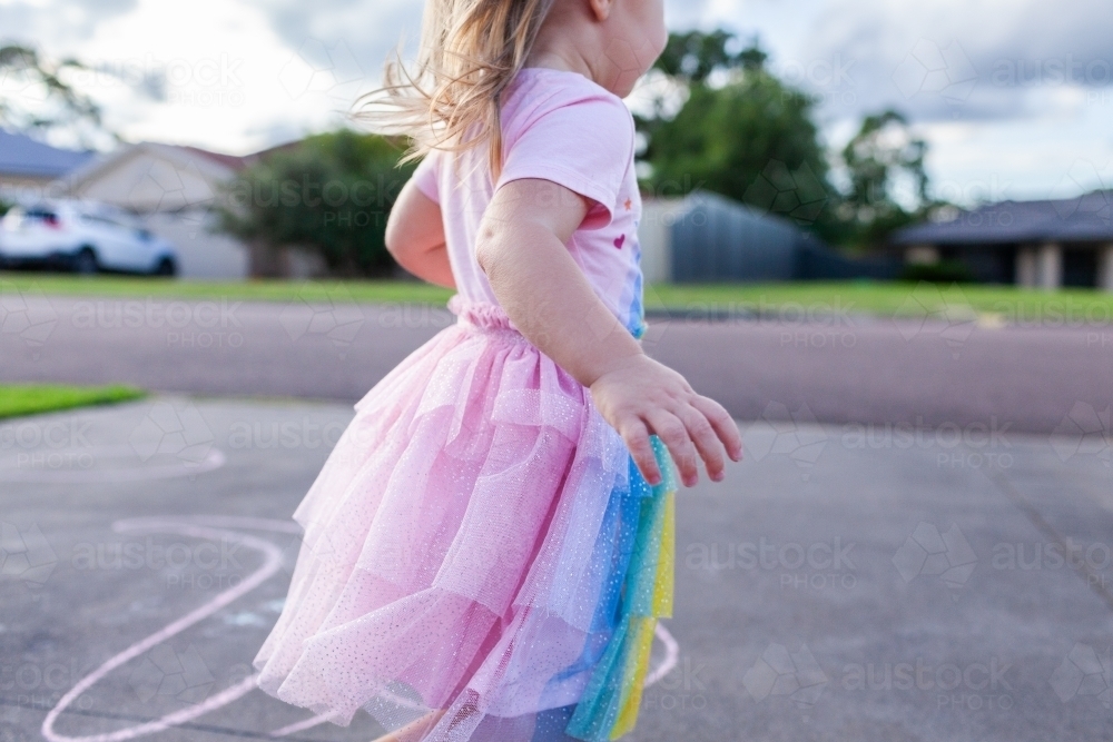 Happy little girl running on suburban driveway enjoying childhood - Australian Stock Image