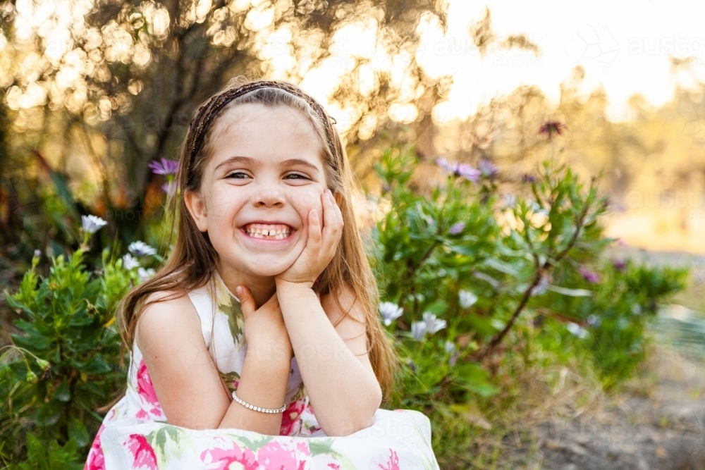 Happy little girl sitting outside in the garden - Australian Stock Image