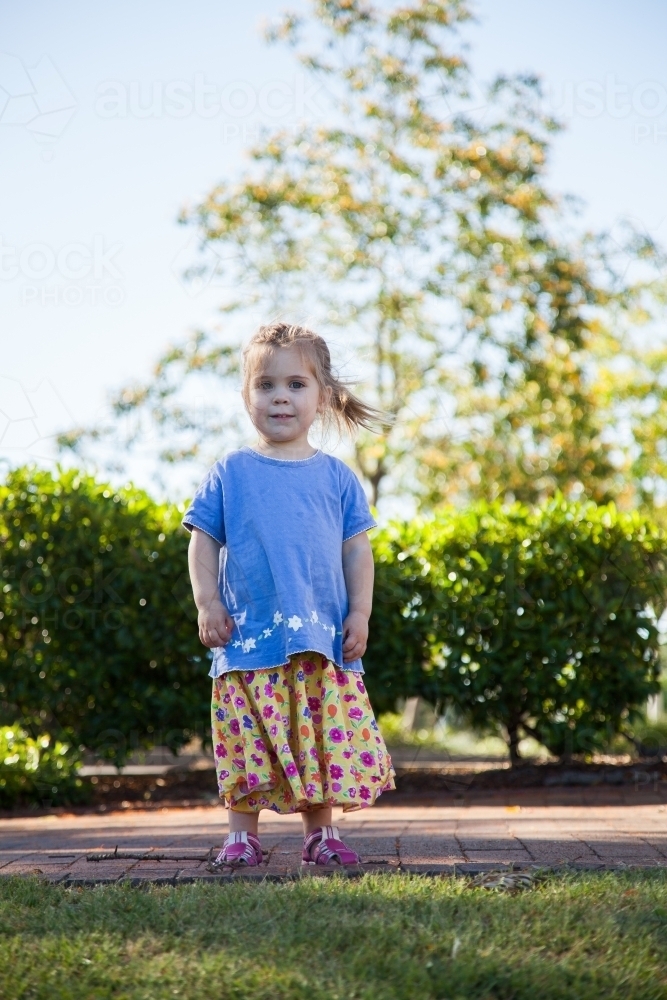 Happy little girl standing outside smiling - Australian Stock Image