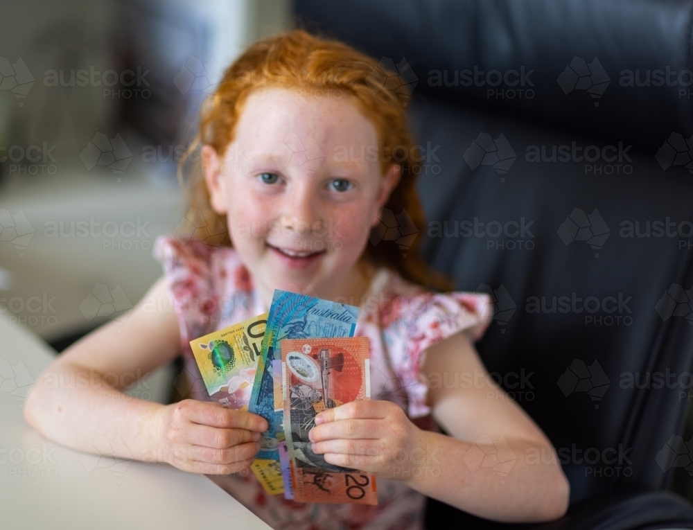 happy little girl with a handful of banknotes - Australian Stock Image