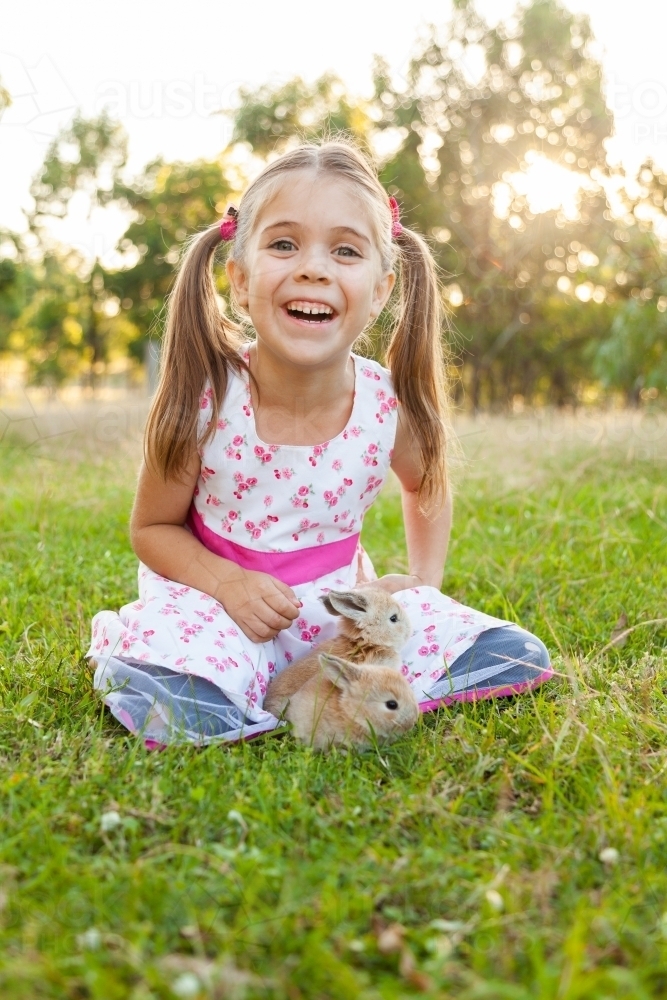 Happy little girl with two real baby Easter bunnies - Australian Stock Image