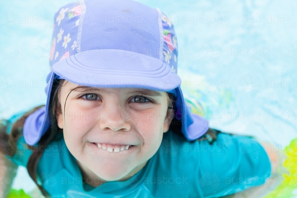 Image of Happy little kid with swimming hat smiling in pool in summer
