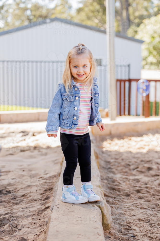 Happy little preschool girl smiling at kindergarten playing outside - Australian Stock Image
