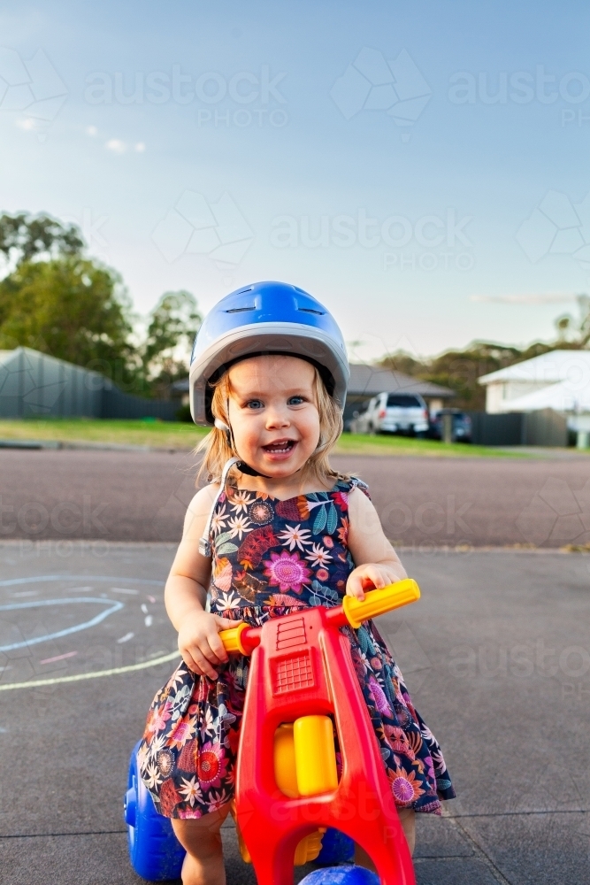 Image of Happy little toddler girl riding trike on driveway on summer ...