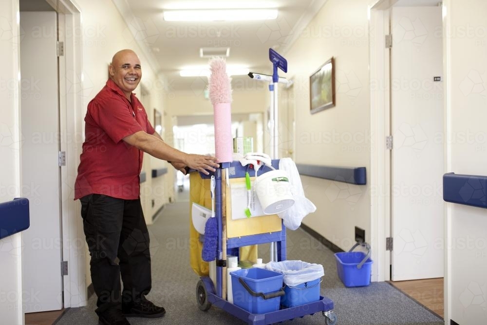 Happy male nursing home cleaner doing rounds - Australian Stock Image