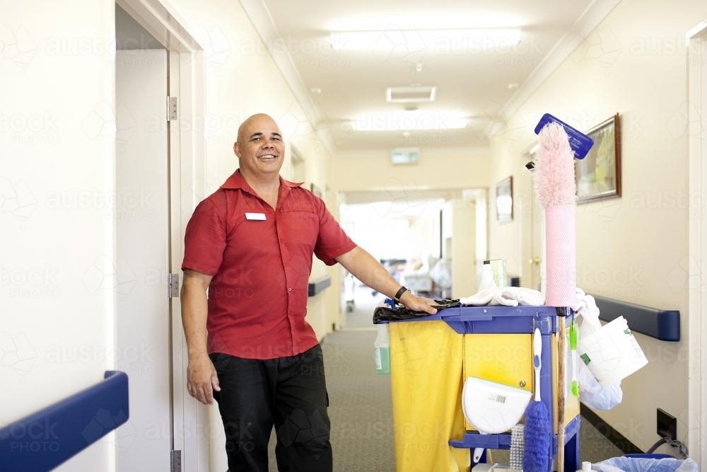 Happy male nursing home cleaner doing rounds - Australian Stock Image