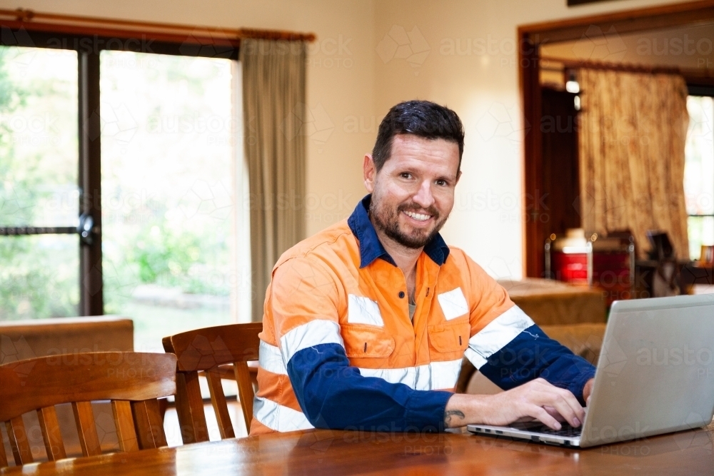 Happy man in his thirties working from home on laptop - Australian Stock Image