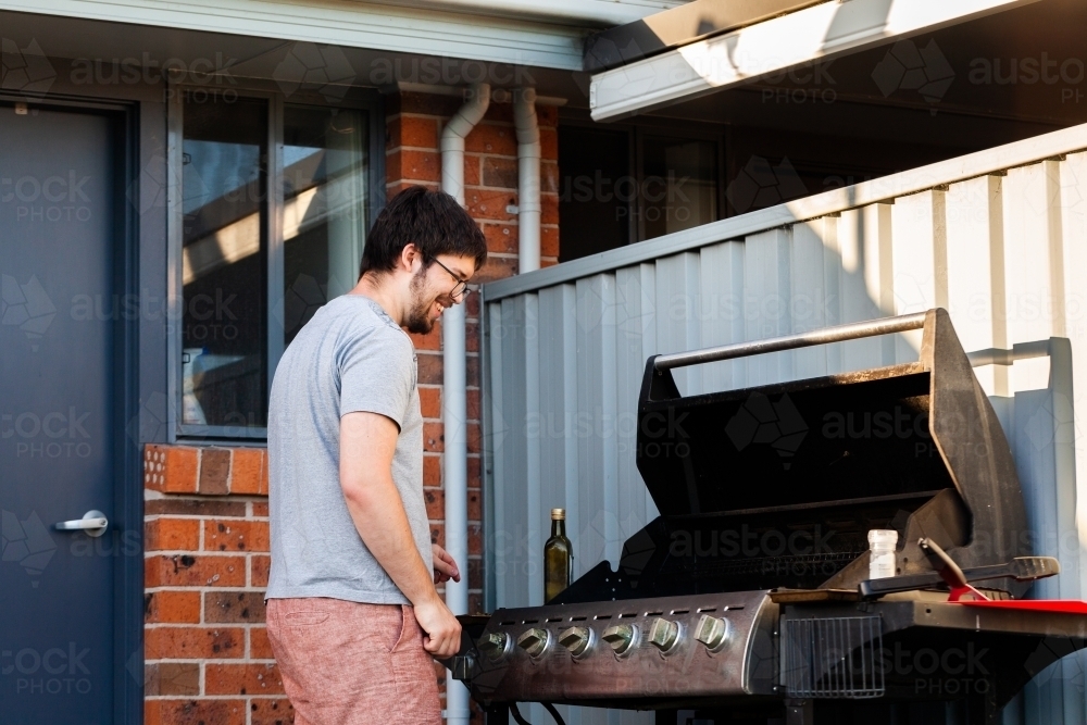 Happy man with meat cooking on his BBQ in the backyard - Australian Stock Image
