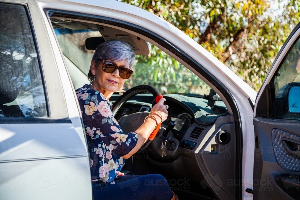 Happy mature aged woman getting into her car - Australian Stock Image