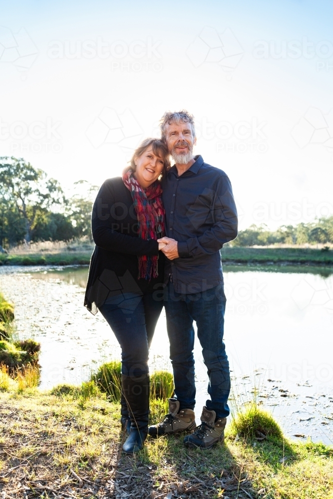 Happy middle aged couple together on farm beside dam - Australian Stock Image