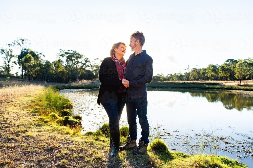 Happy middle aged couple together on farm beside dam - Australian Stock Image