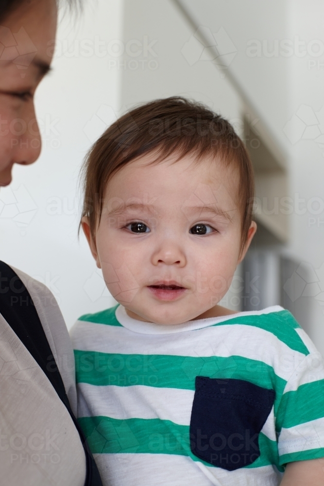 Happy mother holding baby boy in kitchen - Australian Stock Image