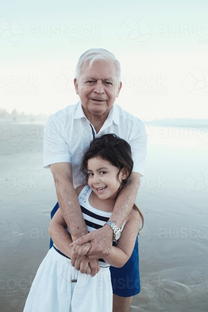 Happy multicultural grandparent with grandchild on the beach - Australian Stock Image