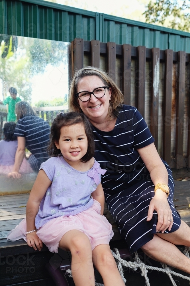 Happy multicultural teacher and child in kindergarten playground - Australian Stock Image