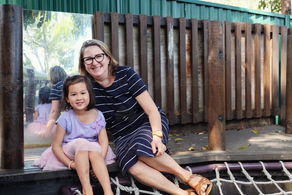 Happy multicultural teacher and child in kindergarten playground - Australian Stock Image