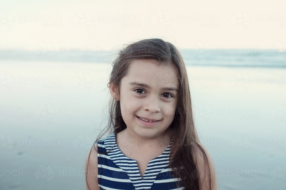 Happy multicultural young little girl on the beach - Australian Stock Image