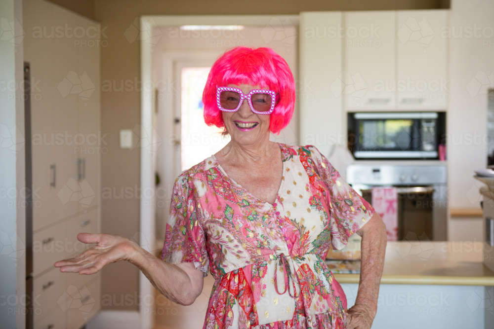 happy older woman wearing a fun pink wig and glasses - Australian Stock Image