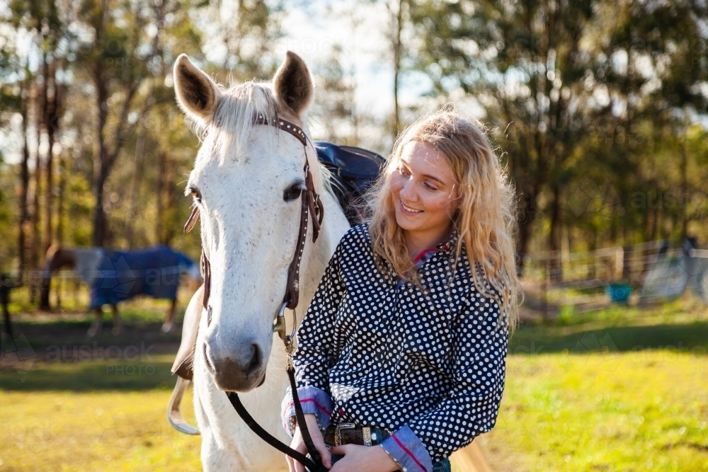 happy person leading her horse through paddock - Australian Stock Image