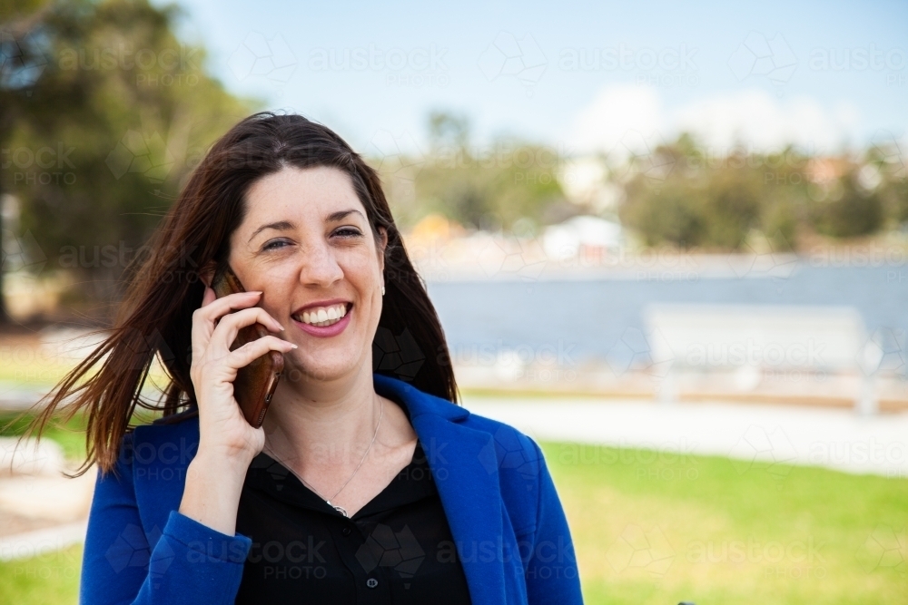 Happy person talking on her phone on a windy day outside - Australian Stock Image