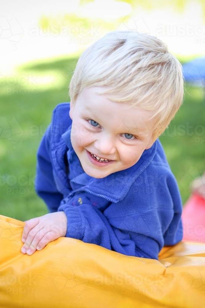Happy preschool age boy playing on gym mat at kindergarten - Australian Stock Image