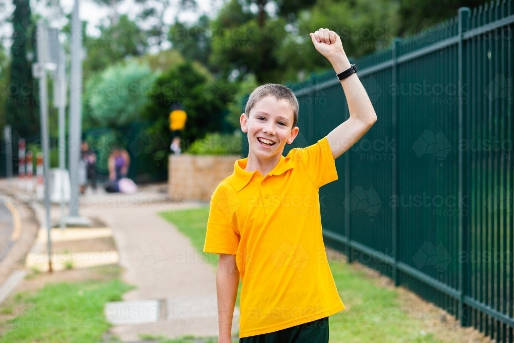 happy primary school boy with arm raised up in celebration - Australian Stock Image