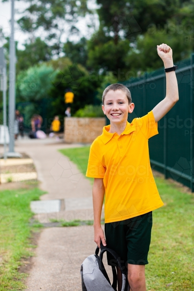 happy primary school boy with arm raised up in celebration - Australian Stock Image