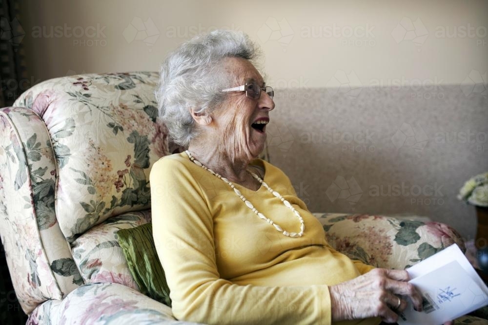 Happy retirement village resident sitting in an arm chair - Australian Stock Image