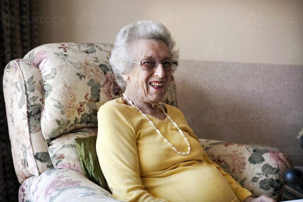 Happy retirement village resident sitting in an arm chair - Australian Stock Image